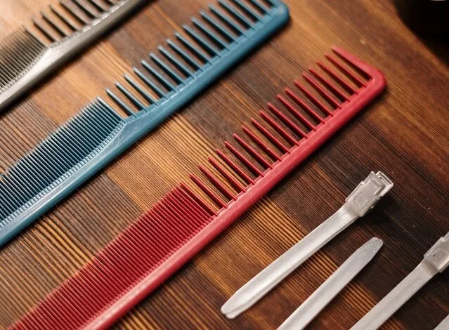 Three combs used for beard and sideburn hair. From left to right; brown comb, blue comb, red comb as well as several smaller hair clips